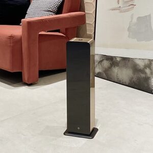 Torre difusora de aromas grandes espacios controlada por aplicación móvil colocada junto a una butaca de diseño moderno.