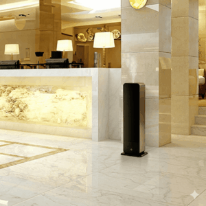 Equipo de torre difusora de aromas grandes espacios instalado discretamente junto al mostrador de recepción de un hotel de alta gama.