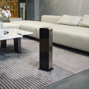 Torre difusora de aromas grandes espacios ubicada de forma elegante en un salón comercial junto a un sofá minimalista.